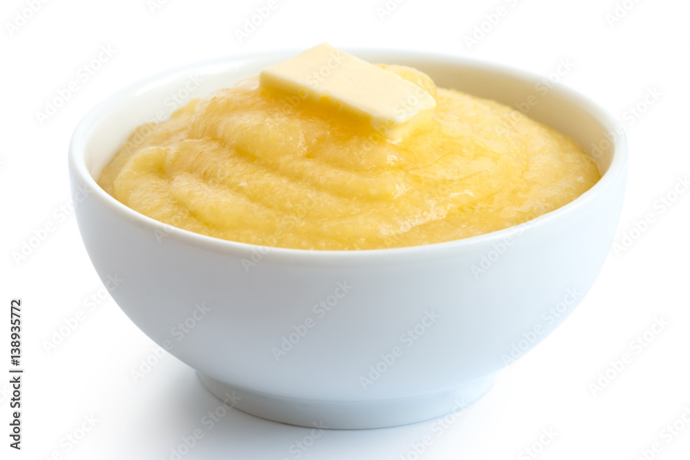 Cooked cornmeal polenta with butter in white ceramic bowl isolated on white.