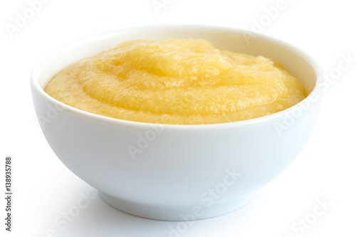 Cooked cornmeal polenta in white ceramic bowl isolated on white.