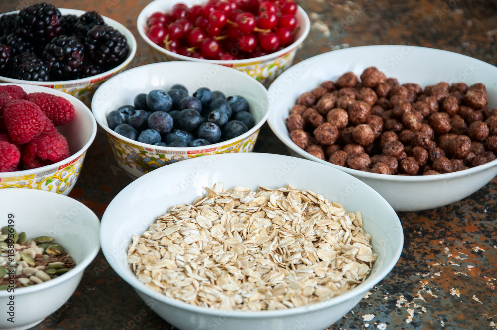 Oat, berries, superfood seeds in bowls on a rusty background Oat, berries, superfood seeds in bowls on a rusty background
