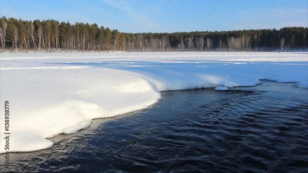 Water flowing out of the lake at the confluence Bugotak River and Karpysak River among the snow cover in winter on the Sunset, Novosibirsk Region, Russia Water flowing out of the lake at the confluence Bugotak River and Karpysak River among the snow cover in winter on the Sunset, Novosibirsk Region, Russia