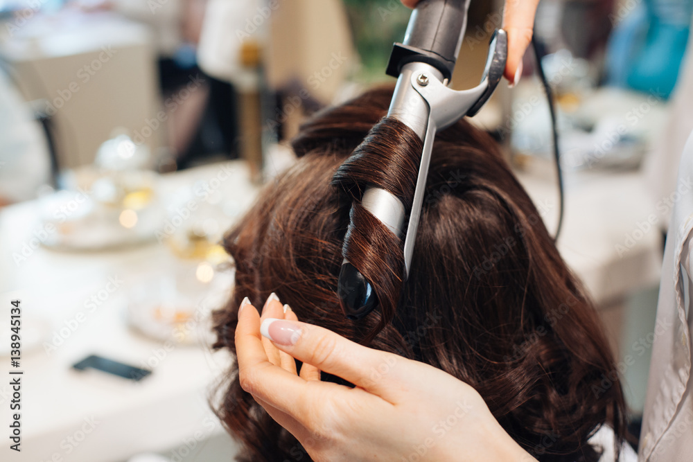 Naklejka premium master in a beauty salon girl doing hairstyle