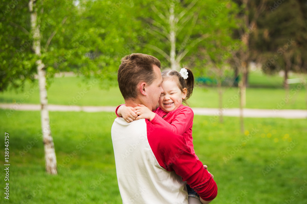 Closeup portrait of happy family. Little funny girl of 4 years age playing outside with her parents in spring city park. Horizontal color photography. Closeup portrait of happy family. Little funny girl of 4 years age playing outside with her parents in spring city park. Horizontal color photography.