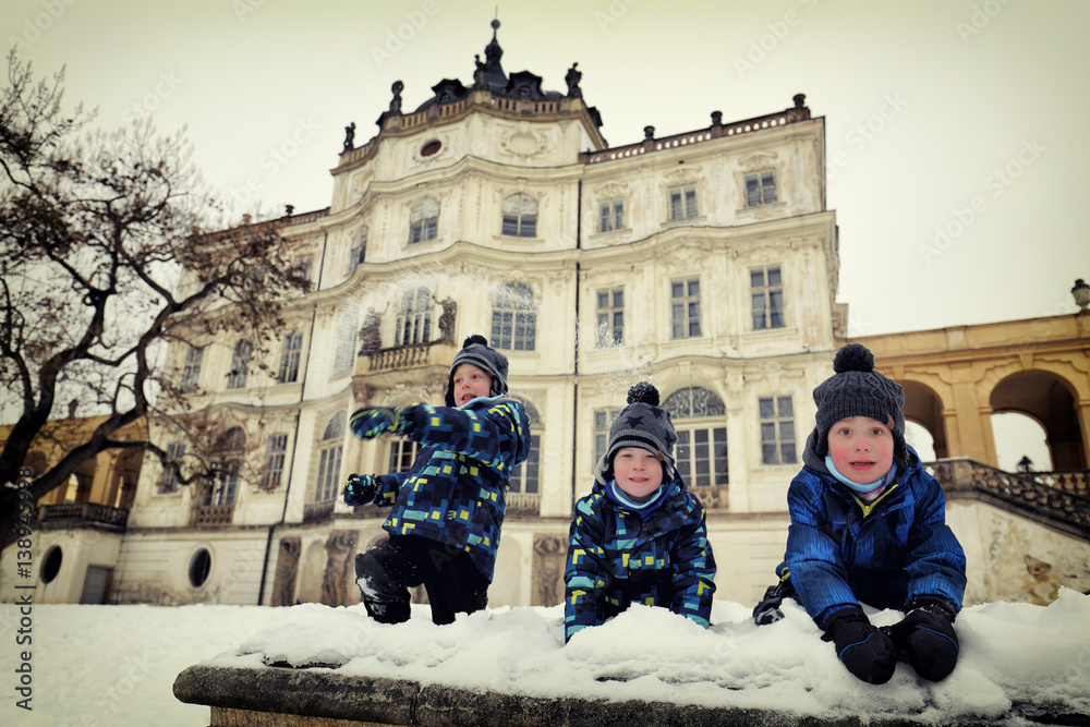 Three boys playing with snow by the chateau
