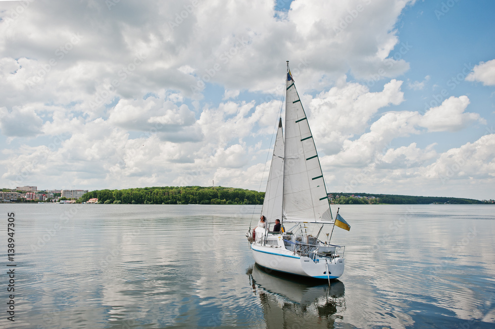 Naklejka premium Wedding couple in love at small sailboat yacht on lake.