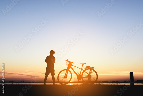 Silhouette of a biker on the hill with sunset background, enjoying freedom and active lifestyle, having fun on a bikers tour