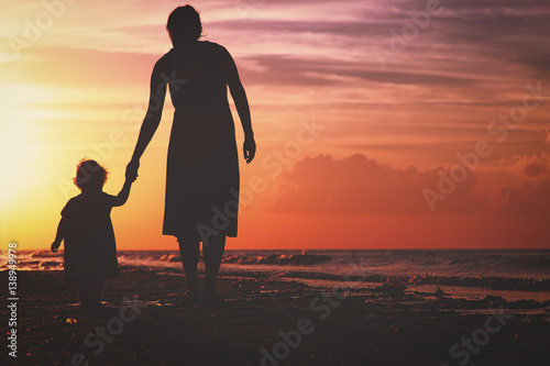 Εκτύπωση καμβά Silhouette of mother and daughter walking on beach at sunset