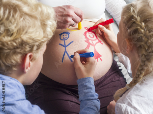 Children painting on pregnant mother's belly