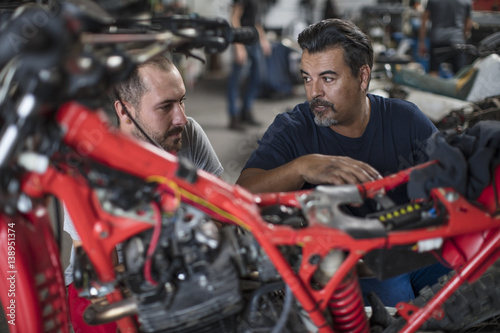 Two mechanics working on motorcycle in workshop together