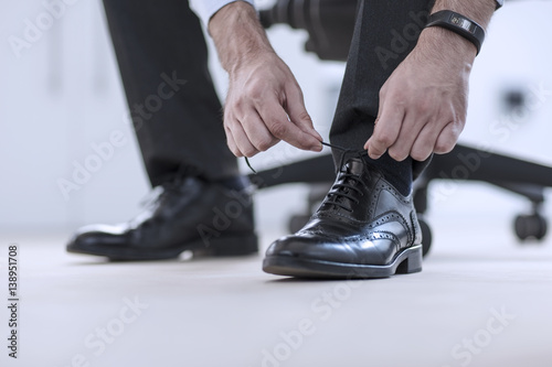 Man tying his black formal shoes photo