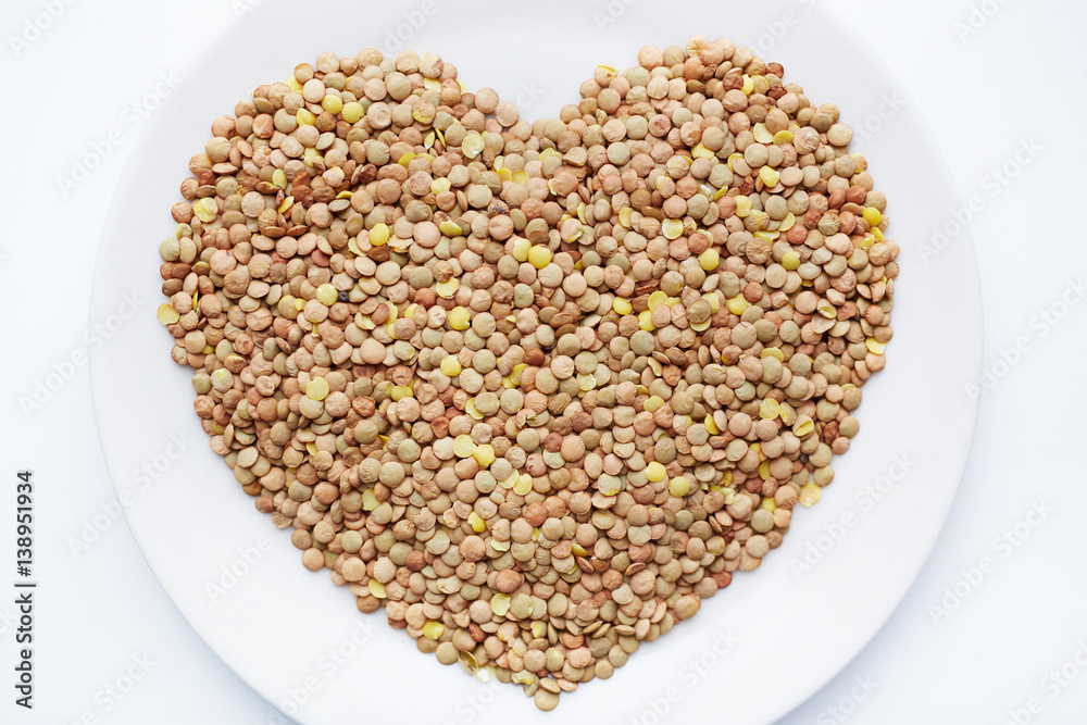Above view of ripe lentil seeds laid out on white porcelain plate in shape of heart Above view of ripe lentil seeds laid out on white porcelain plate in shape of heart