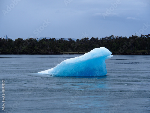 Small blue iceberg floating in cold sea photo