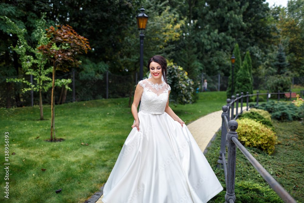 beautiful and young bride in white dress walking in the garden
