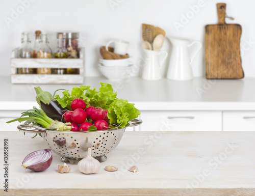 Fresh vegetables on wooden table over blurred kitchen counter interior