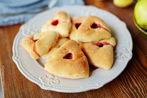 Close-up view of freshly baked triangular raspberry buns lying on white elegant plate