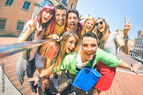 Group of multicultural tourists friends having fun taking selfie and shouting out at old town tour -Travel lifestyle concept with happy people wandering around city landmarks - Vivid saturated filter photo
