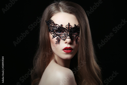 Beauty portrait of sexy mysterious woman in lace mask on a black background.