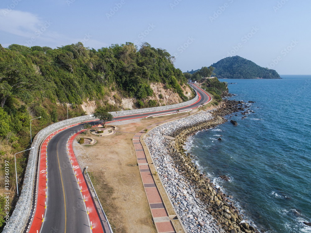 Road laying along the sea at the edge of hill in aerial view