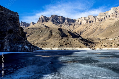 замерзшее озеро в горном ущелье, весна, горные склоны, природа Северного Кавказа, красивый пейзаж