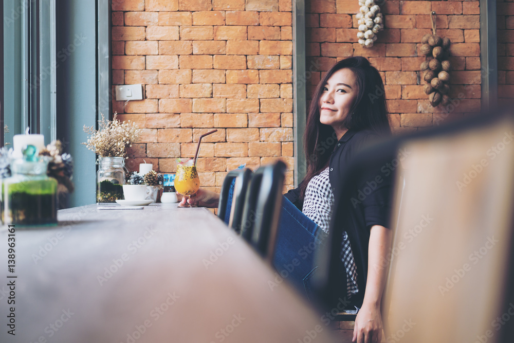 Beautiful Asian woman sitting in modern cafe with orange juice and ...