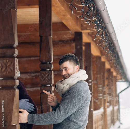 Man looks funny touching woman's pregnant belly while she hides on wooden porch