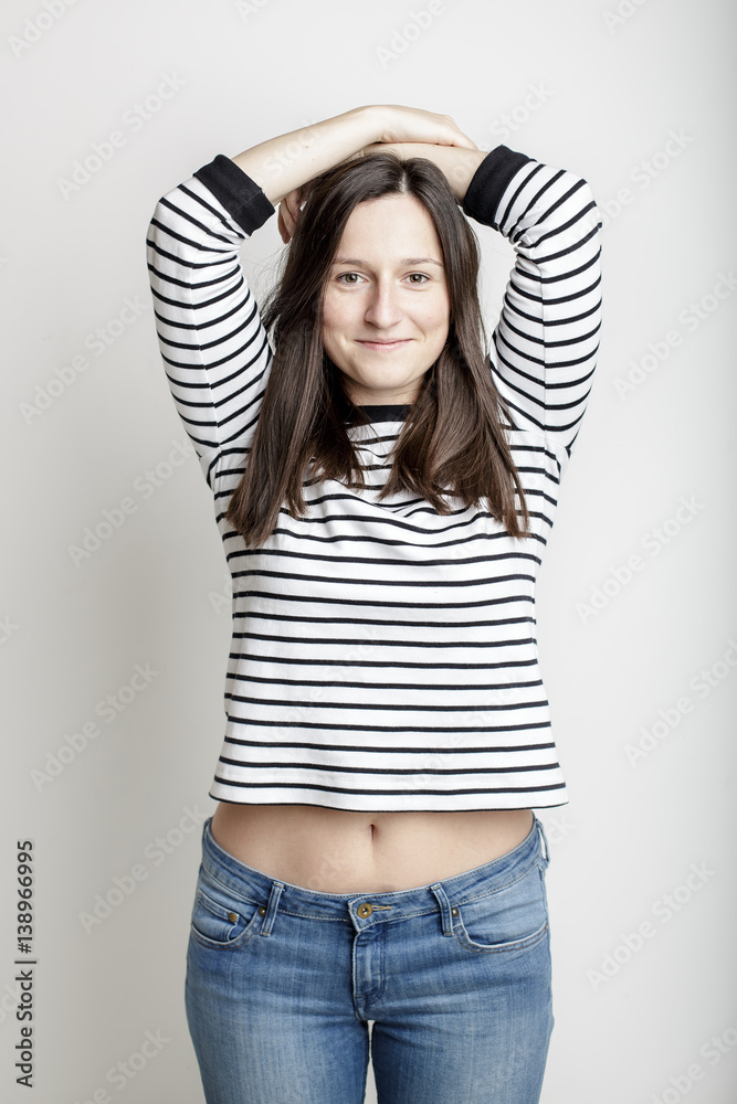 girl in blue jeans and a striped sweater and lifted her arms bared belly  with a beautiful waist and umbilicus Stock Photo | Adobe Stock