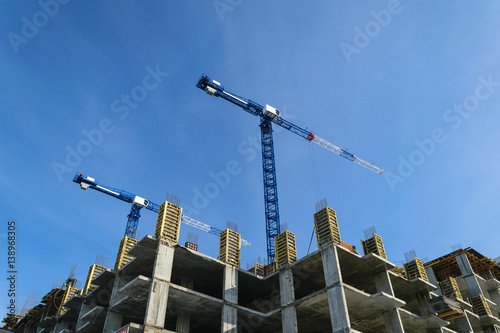 constructionsite with two bulding cranes agenst blue sky