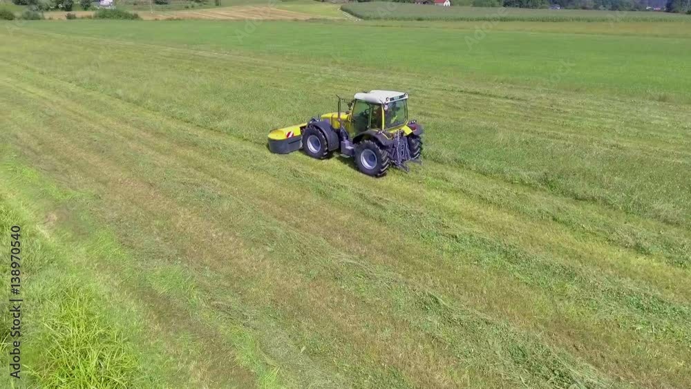 A yellow tractor is busy working outside on a hot summer day. It is cutting grass with a special agricultural machinery.
A yellow tractor is busy working outside on a hot summer day. It is cutting grass with a special agricultural machinery.