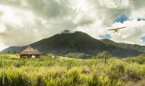 plane flying over huts in remote tropical location