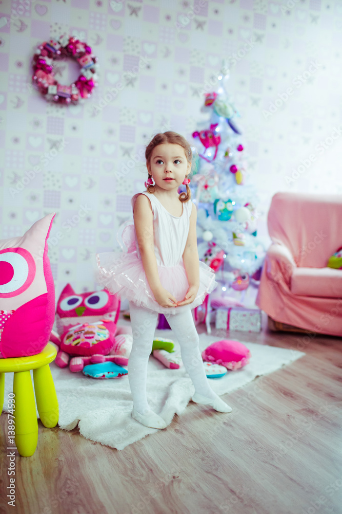 Fototapeta premium Child looks funny posing in ballet-dancers dress in play-room