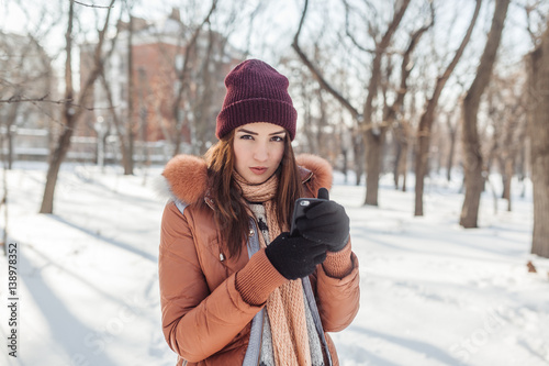 The girl walks in the park in good sunny day. She resolves some issues in phone. The girl has a stare, she as if sees us through.