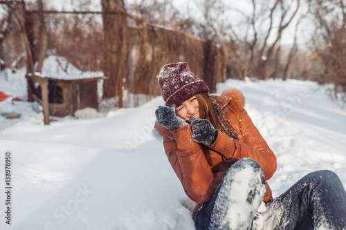 The girl walks in excellent snow day. She has fallen to snow and laughs loudly. All her things in snow. She rejoices and very ridiculously looks. The girl in fine mood. photo