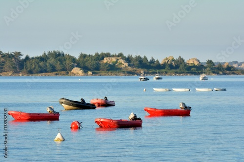 Canots rouges de l'école de voile au mouillage dans la baie de Port-Blanc à Penvénan en Bretagne © aquaphoto