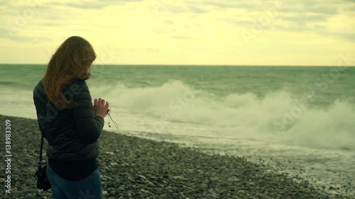 The Lonely Woman With The Smartphone in a Hand Looks at the Winter Sea