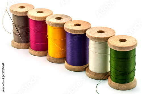 Isolated wooden spools of thread with a needle