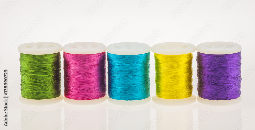 Row of colorful bright thread and bobbin Row of colorful bright thread and bobbin