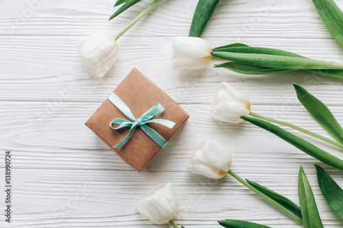stylish craft present box and tulips on white wooden rustic background. flat lay with flowers with space for text. hello spring. happy day concept. instagram photo workshop
