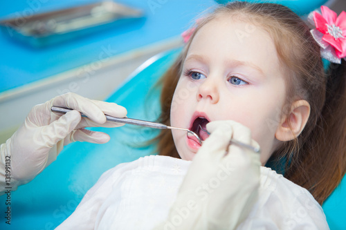 Close-up of pretty little girl opening his mouth wide during inspection of oral cavity at the dentist