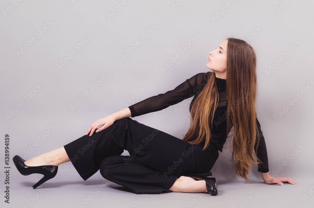 Beautiful woman in black clothes posing for the camera portrait young studio on gray. Pink toning Beautiful woman in black clothes posing for the camera portrait young studio on gray. Pink toning