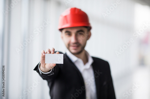 Construction worker holding blank business card in building construction. photo