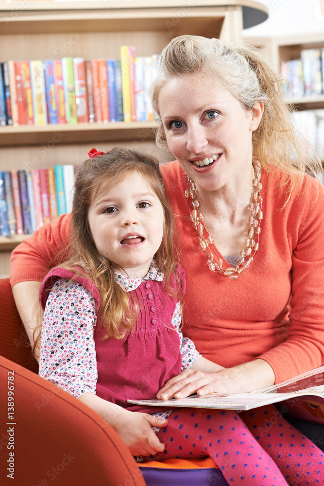 Fototapeta premium Mother And Daughter Reading Book In Library