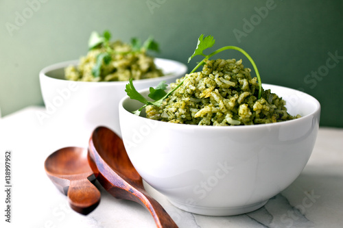 Green rice in bowls with wooden spoons photo