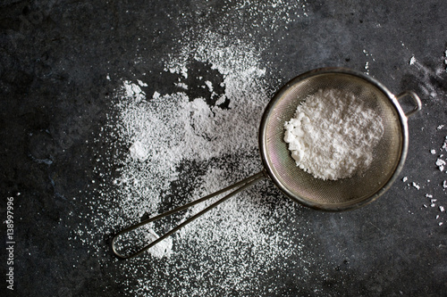 Work surface with flour in sieve, overhead view photo