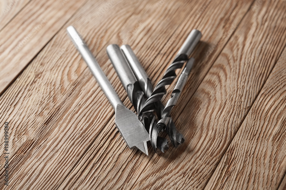 set of different drill bits on wooden background set of different drill bits on wooden background