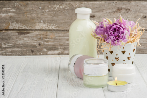 Beauty products, cosmetics, lit candle and purple tulips