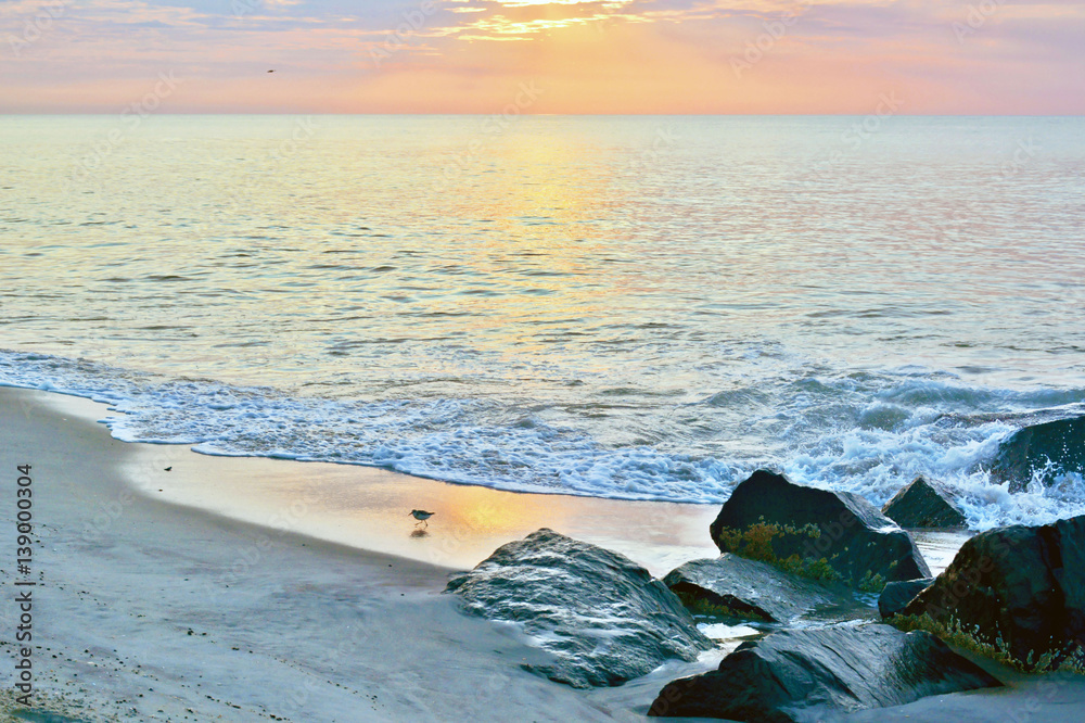 Naklejka premium Scenic Summer Seashore Sunrise Over Rock Jetty on the Beach