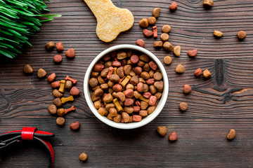 dry dog food in bowl on wooden background top view