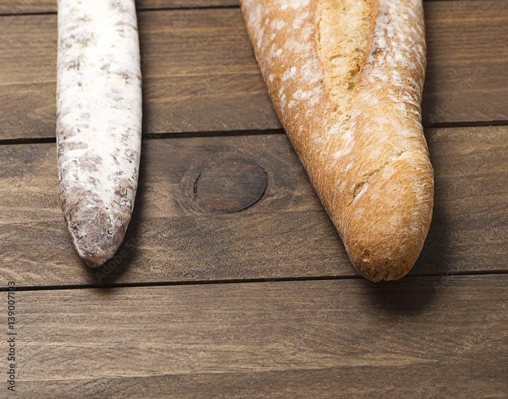 Bread fuet on wooden table. Spanish sausage. Horizontal shoot. - obrazy, fototapety, plakaty 