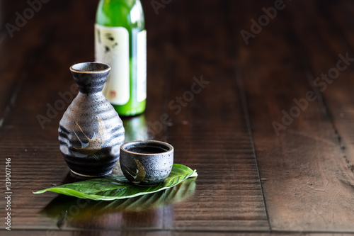 Japanese sake set and a bottle of sake on the rustic wood table.