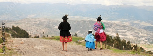 Traditional Peruvian woman with child in Ayacucho Peru walking in highlands of the Andes mountains photo