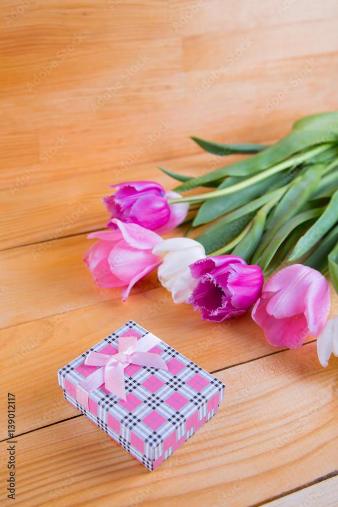 Bouquet of tender pink tulips with gift box on light wooden background Bouquet of tender pink tulips with gift box on light wooden background